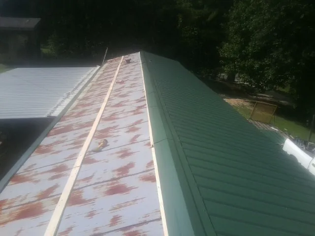 Old rusted panels beside newly installed green metal roofing — Wind Damage Roof Repair by Roofing Brothers in Stites