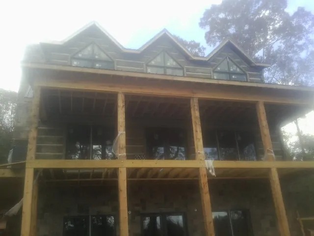 Dormers and porch framing on a large log home under construction — Roof Coating work by our crew in Stites