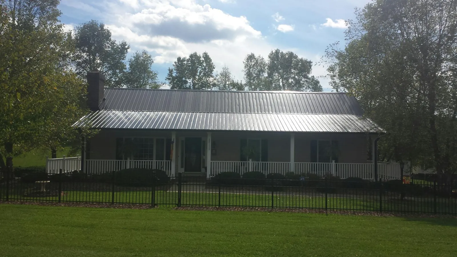 Gray metal roof on a brick ranch with a full width front porch — Gutter Guard Installation work by our crew in Stites