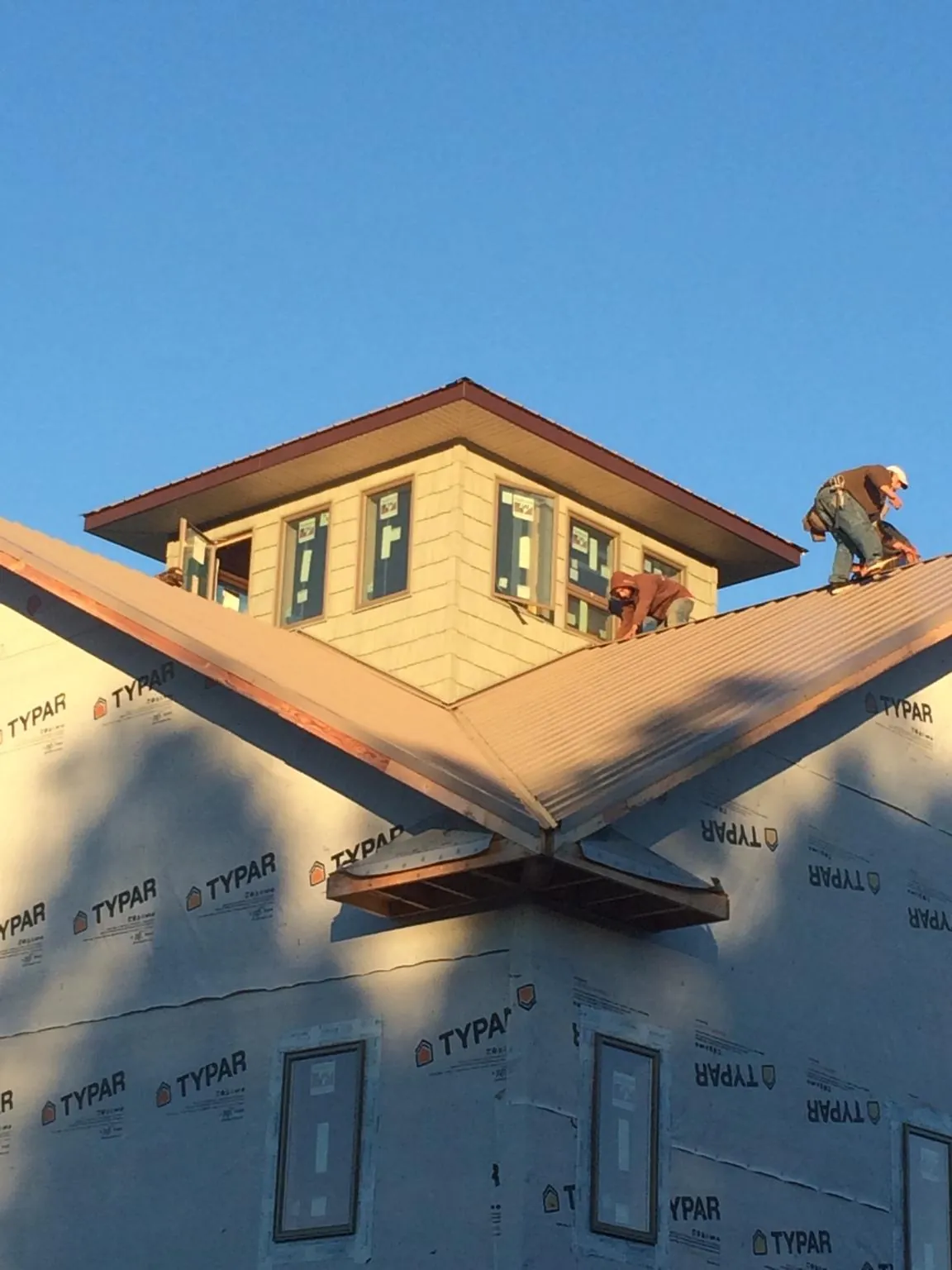 Roofers working around a rooftop cupola on a new metal roof at sunset — Roof Waterproofing in Stites by Roofing Brothers